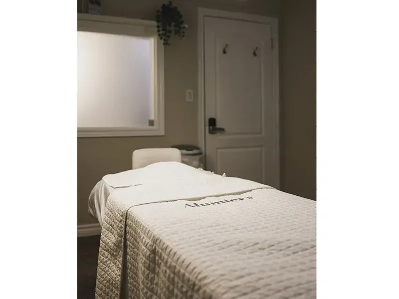 A massage table in a room with a white towel on it.