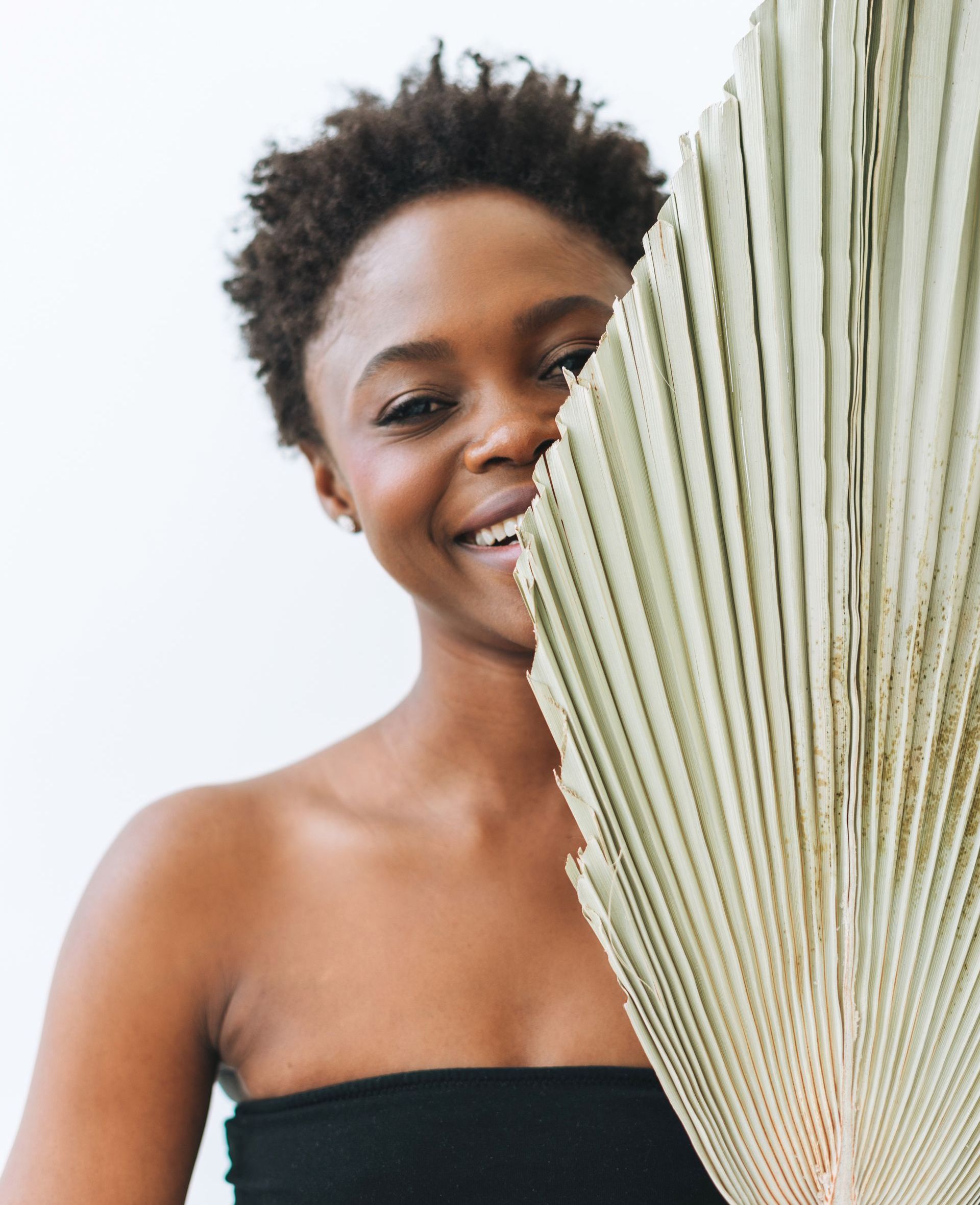 beautiful african american woman smiling behind plant