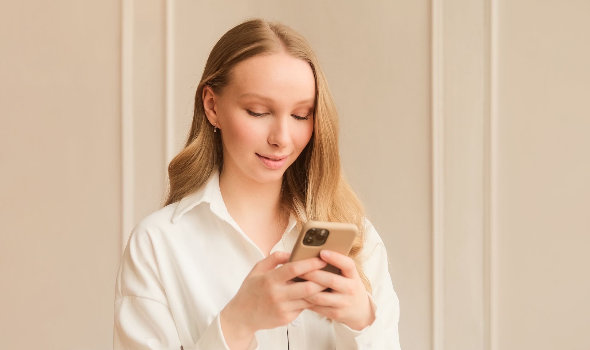 A woman in a white shirt is using a cell phone.