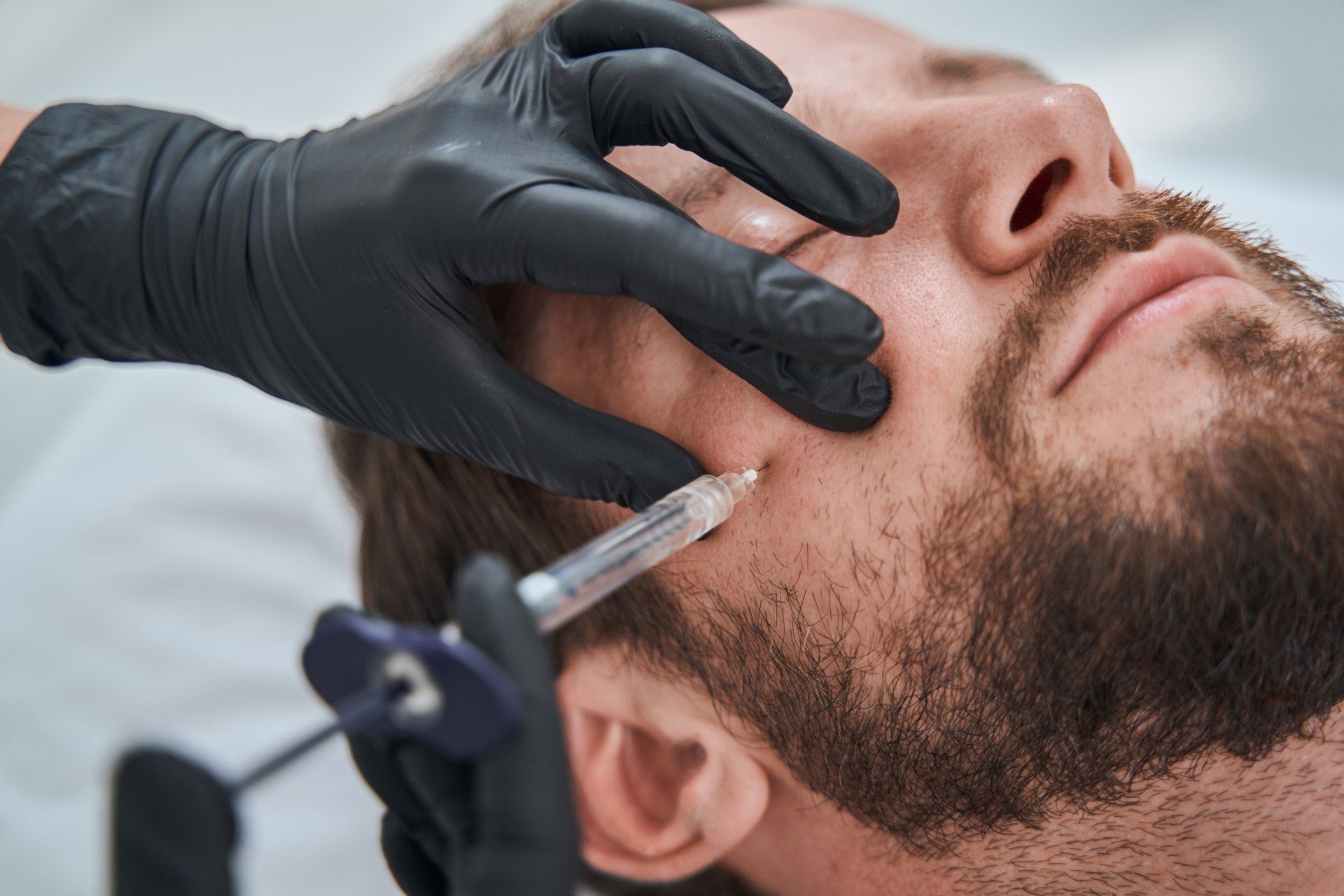 Caucasian man receiving Botox injections in his right cheek