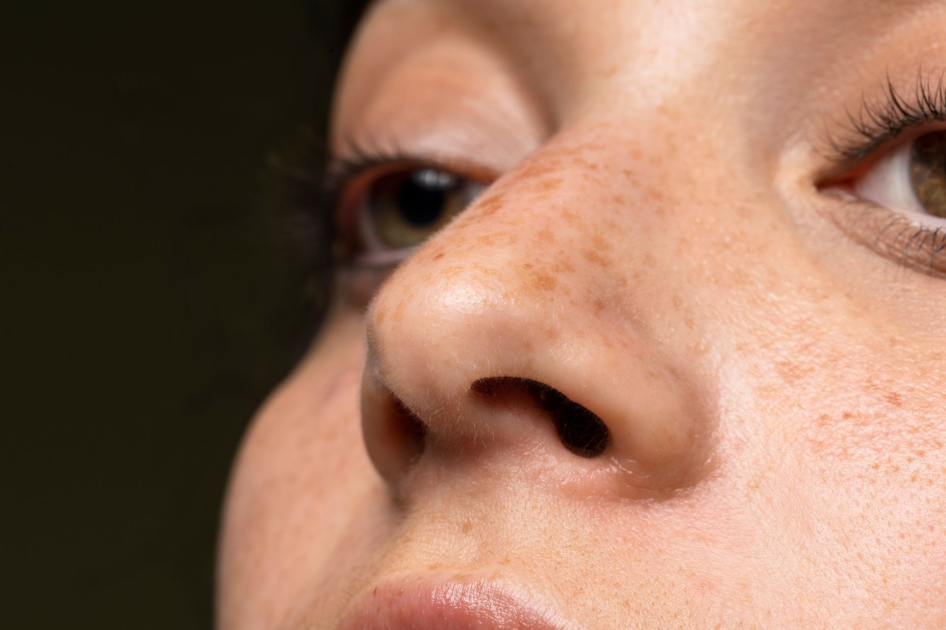 A close up of a woman 's nose with freckles.