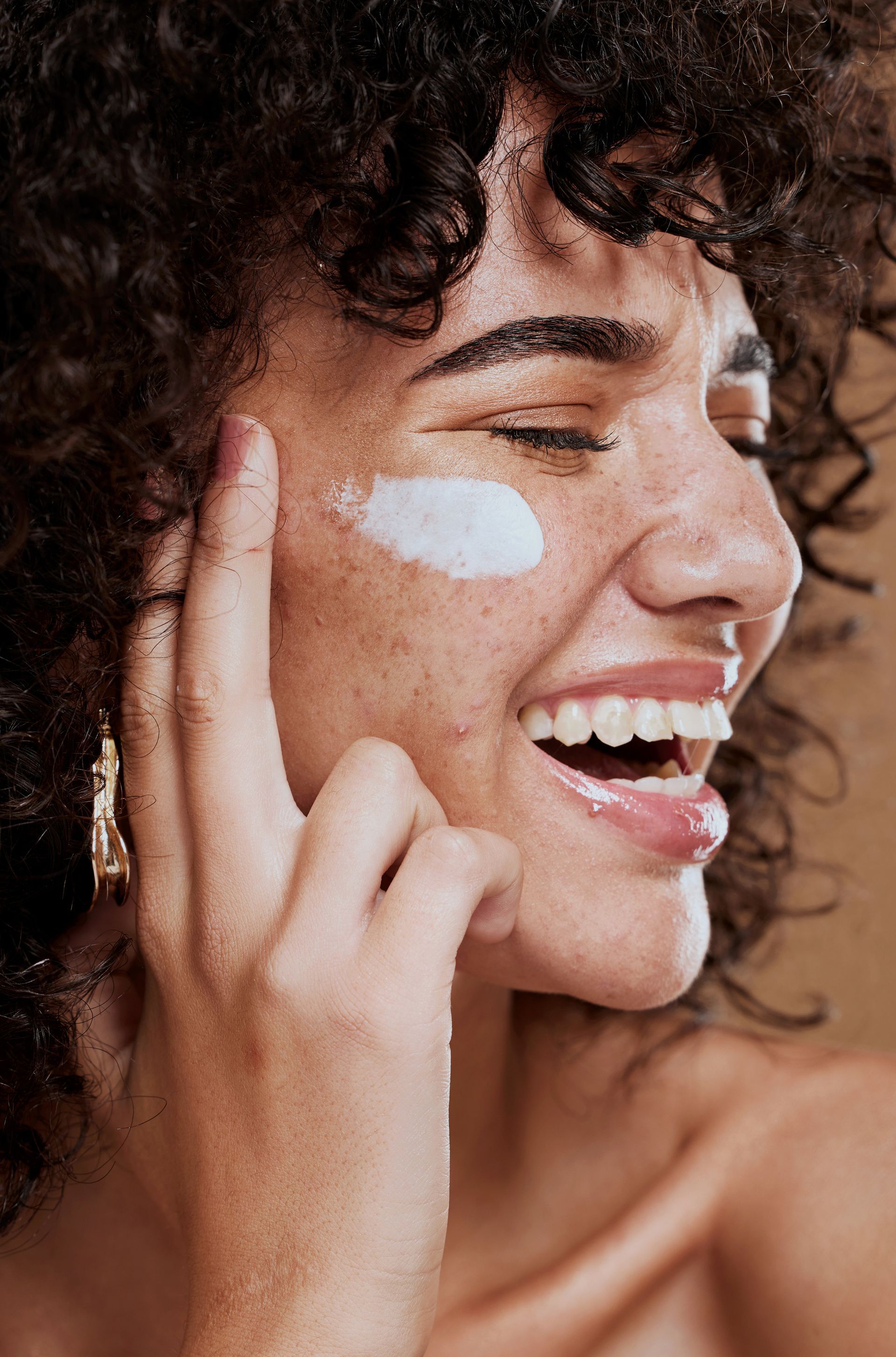 happy woman applying face cream 