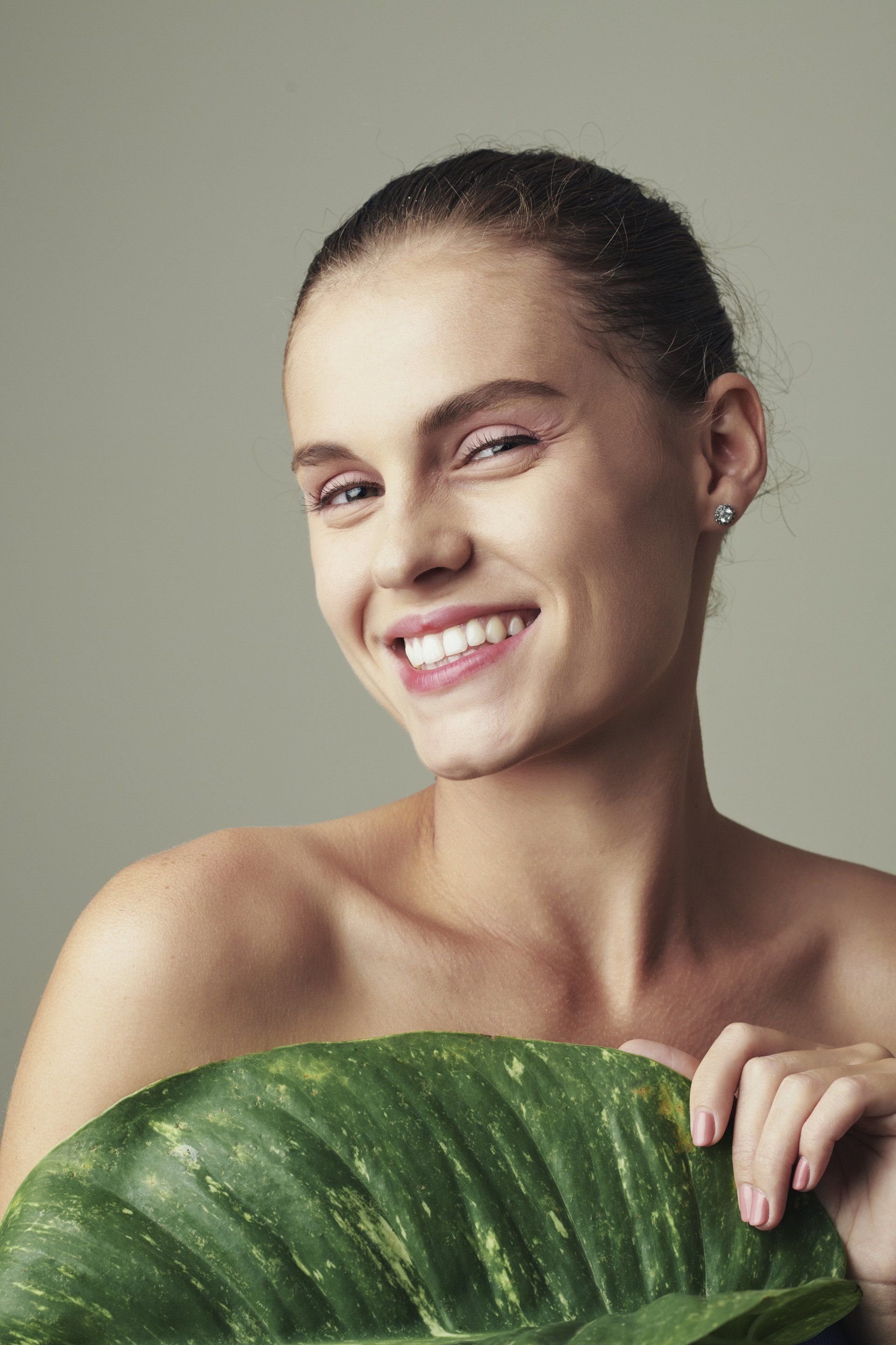 happy woman smiling with big green leaf in front of chest
