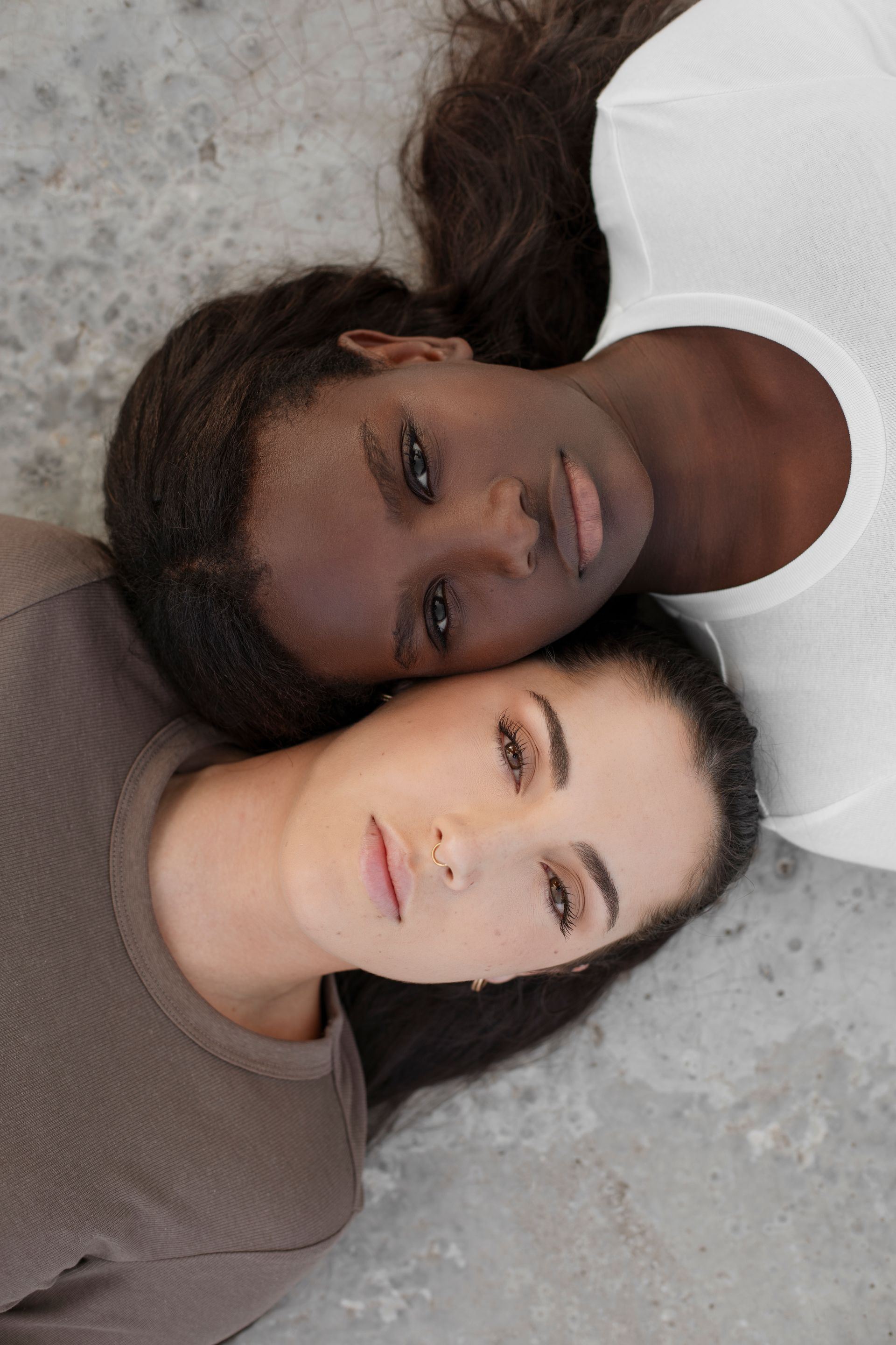 Two women are laying next to each other on the ground.