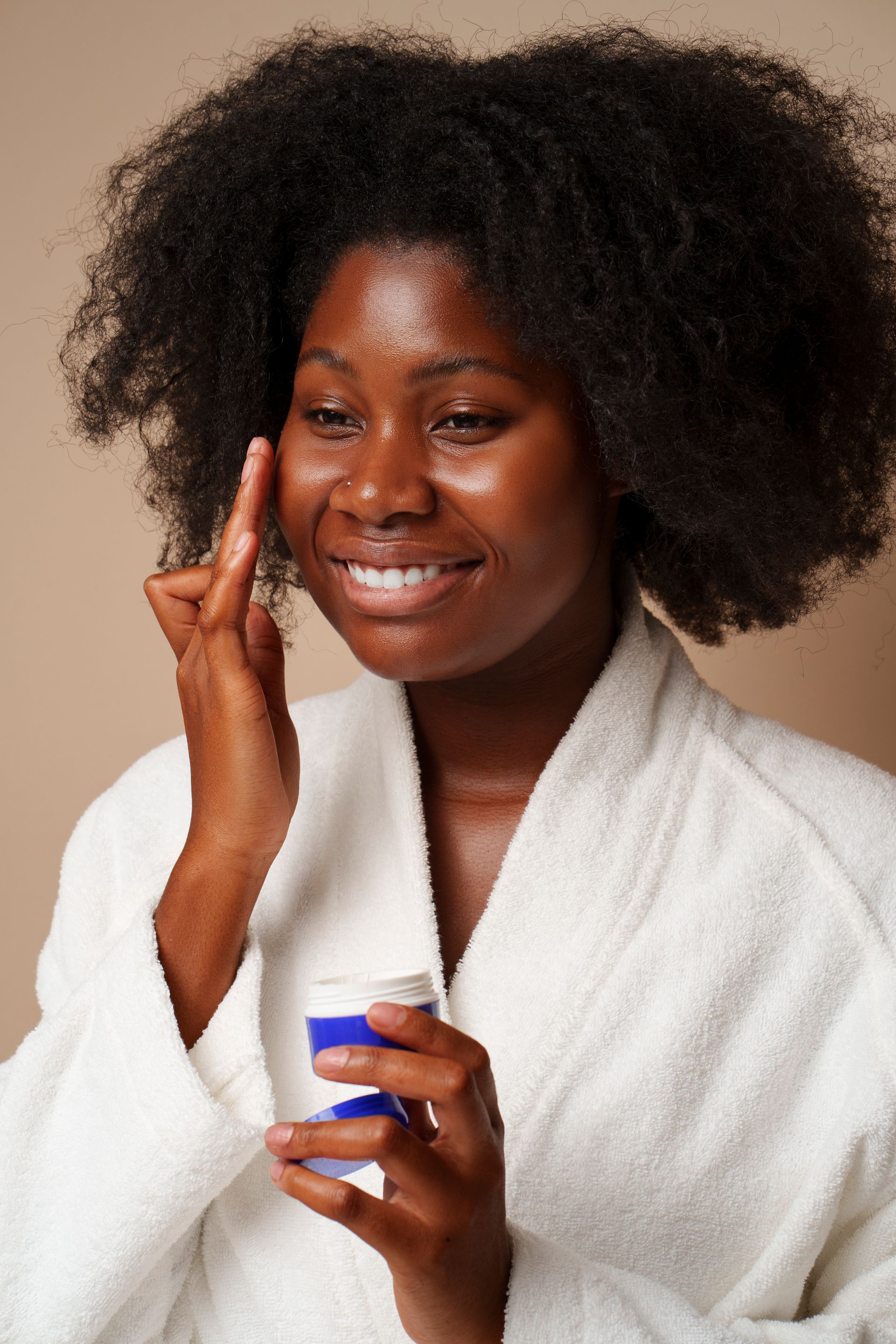 portrait of african american woman applying cream 