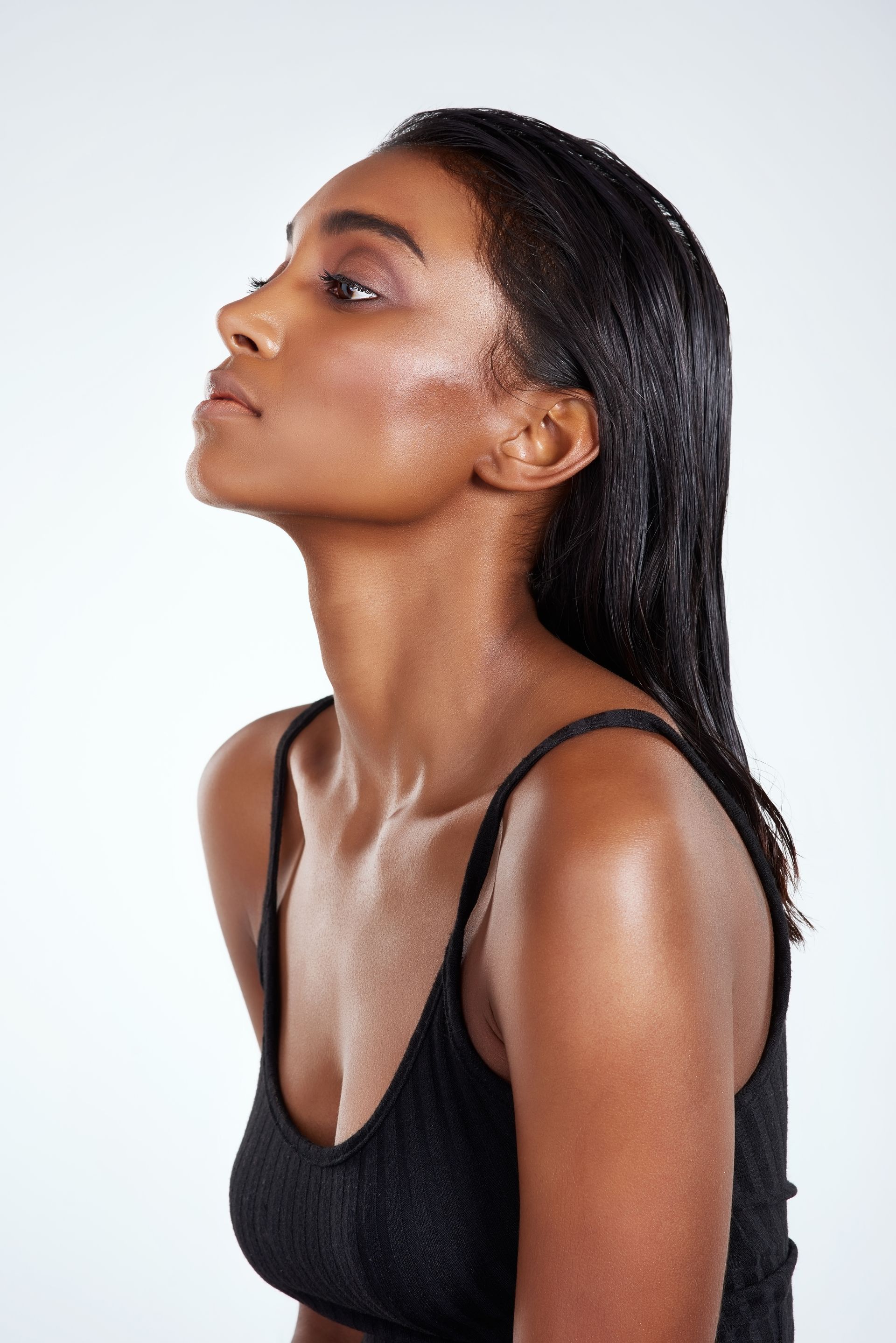 A woman in a black tank top is looking up.