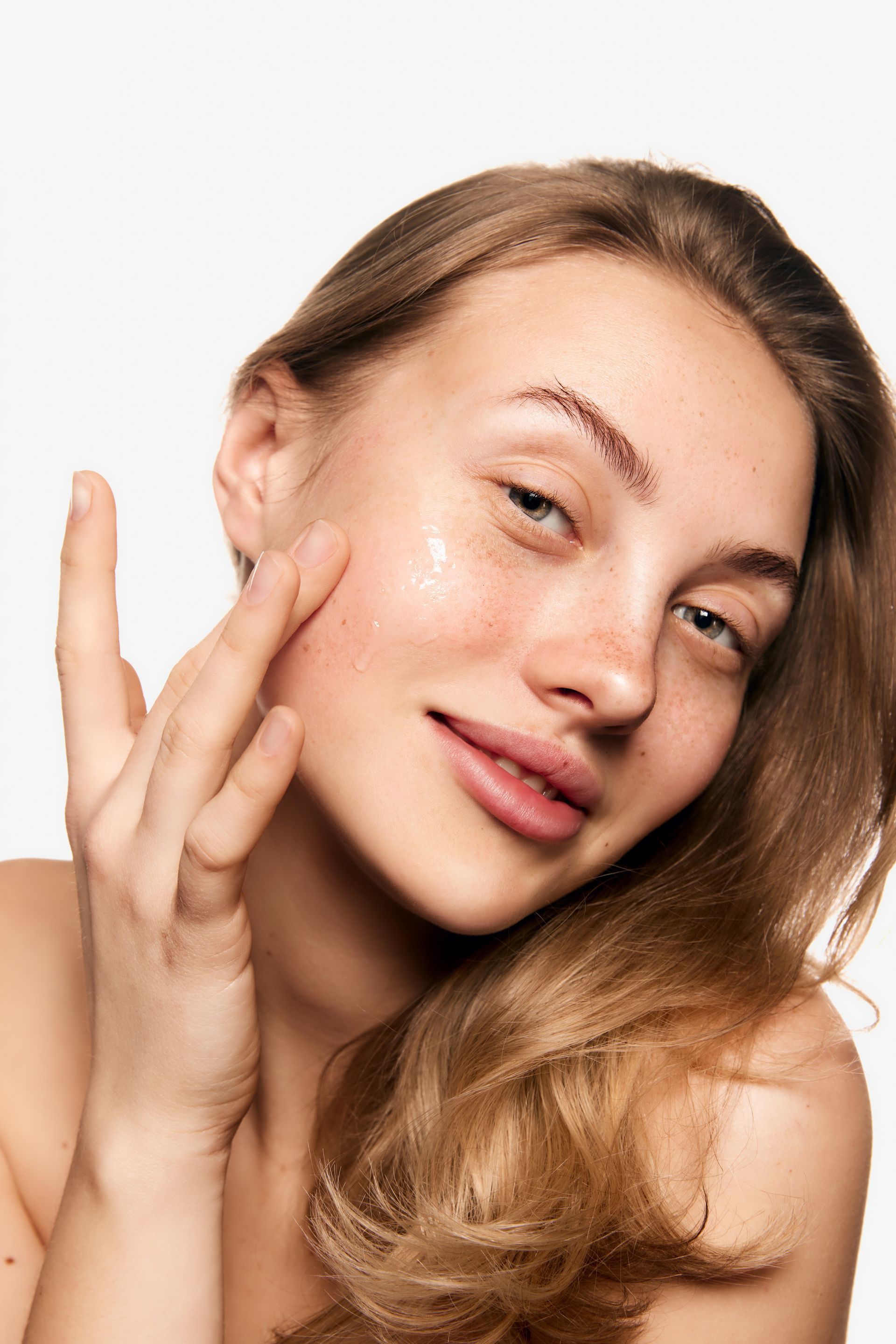 A woman is applying a cream to her face.