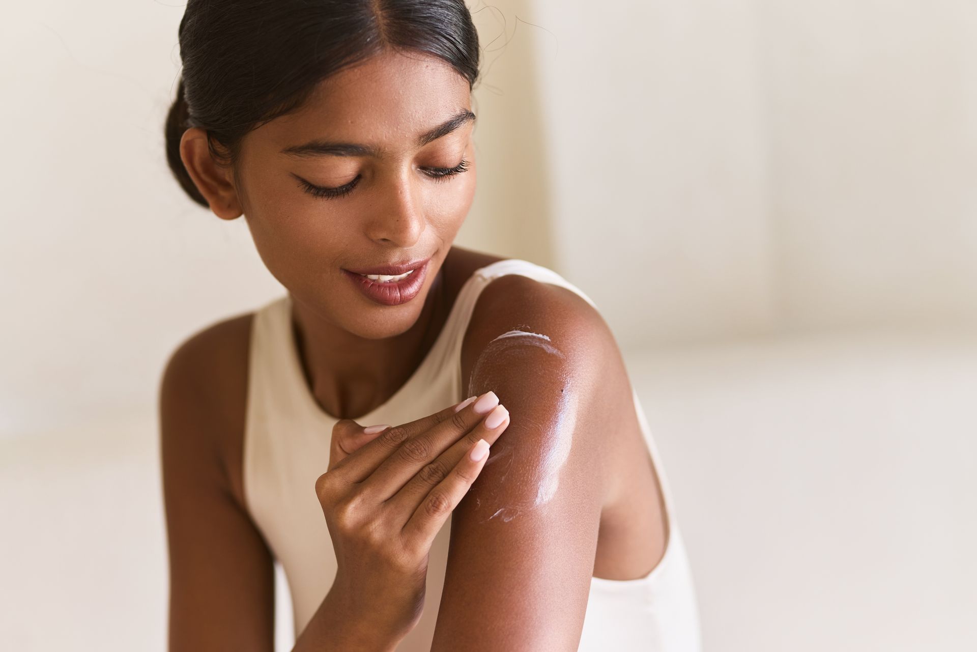 A woman is applying lotion to her arm.