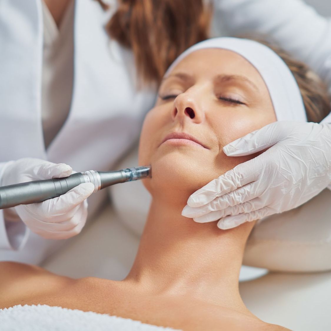 cosmetologist applying anti aging injections into forehead