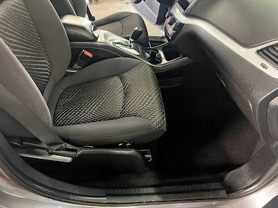 The inside of a car with the seats up and the door open.