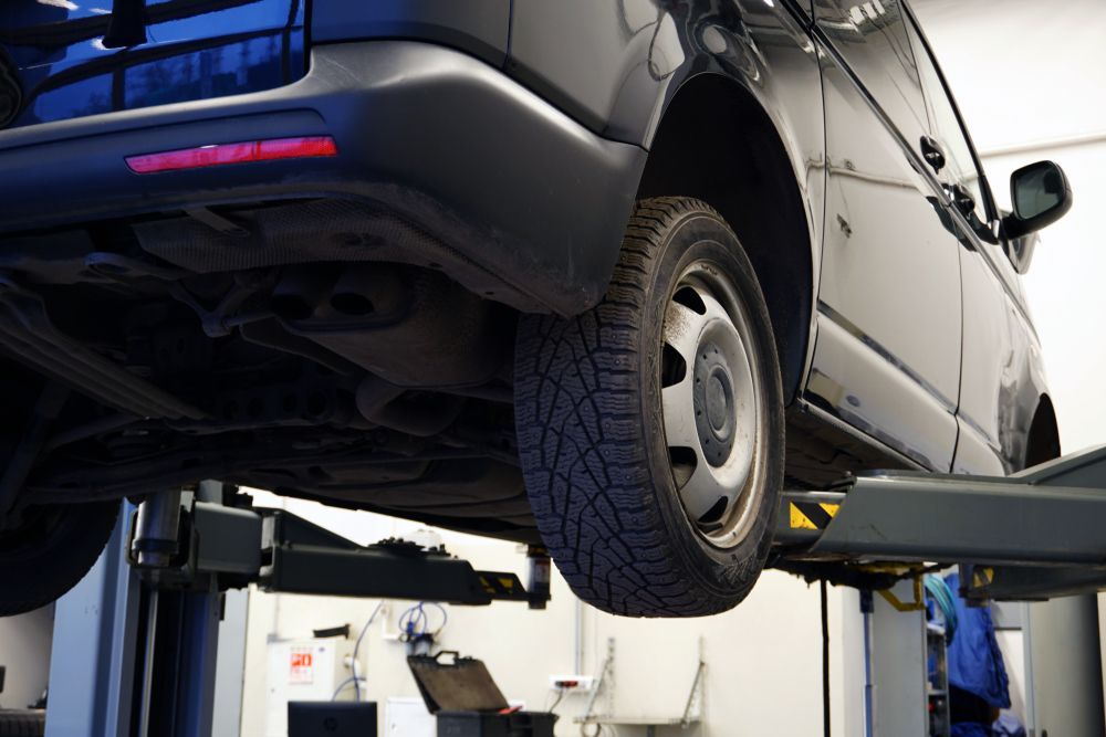 A black van is sitting on a lift in a garage.