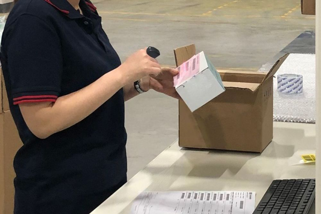 Logistics staff using wearable ring scanner to process and check package in warehouse operation