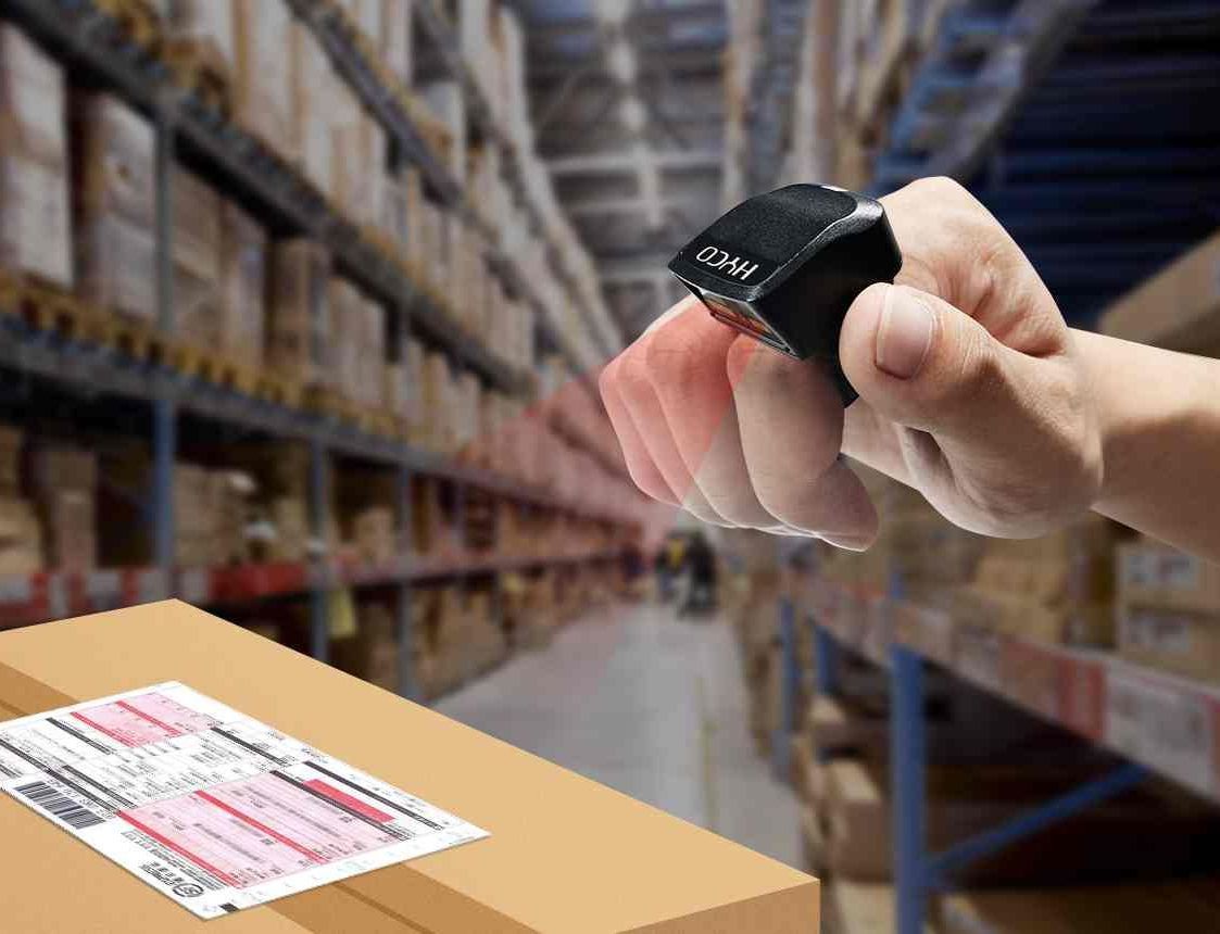 A person is using a barcode scanner to scan a box in a warehouse.