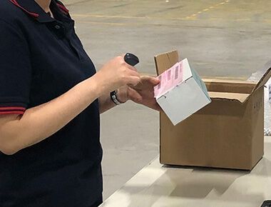 A woman wearing Hyco Ring Scanner is holding a cardboard box in front of a cardboard box.