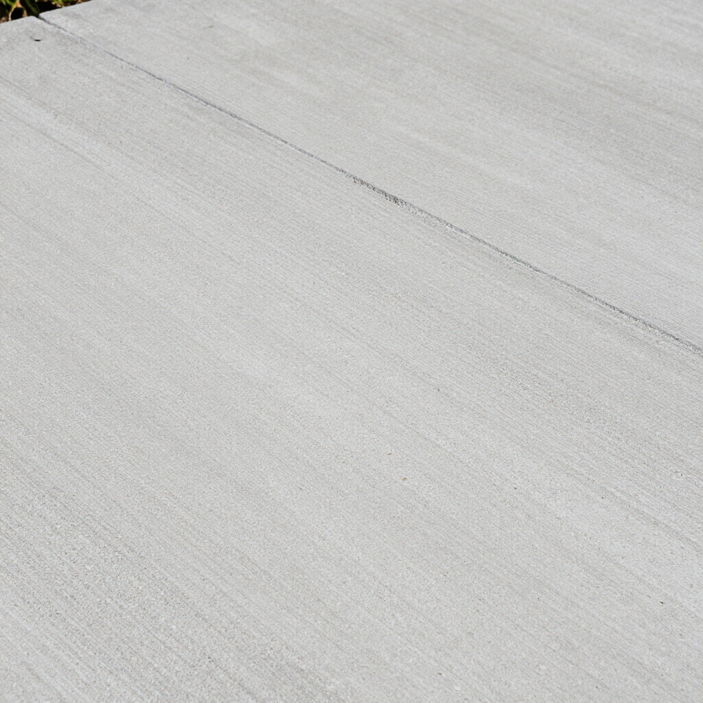Close-up of a light gray concrete surface with a straight, dark joint line running diagonally across the texture.