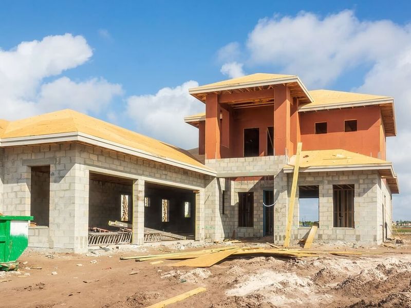 Construction site: Two-story house under construction with a garage. Red stucco and concrete block walls.
