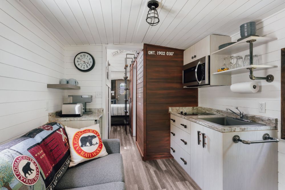 A living room with a couch and a kitchen in a small house.