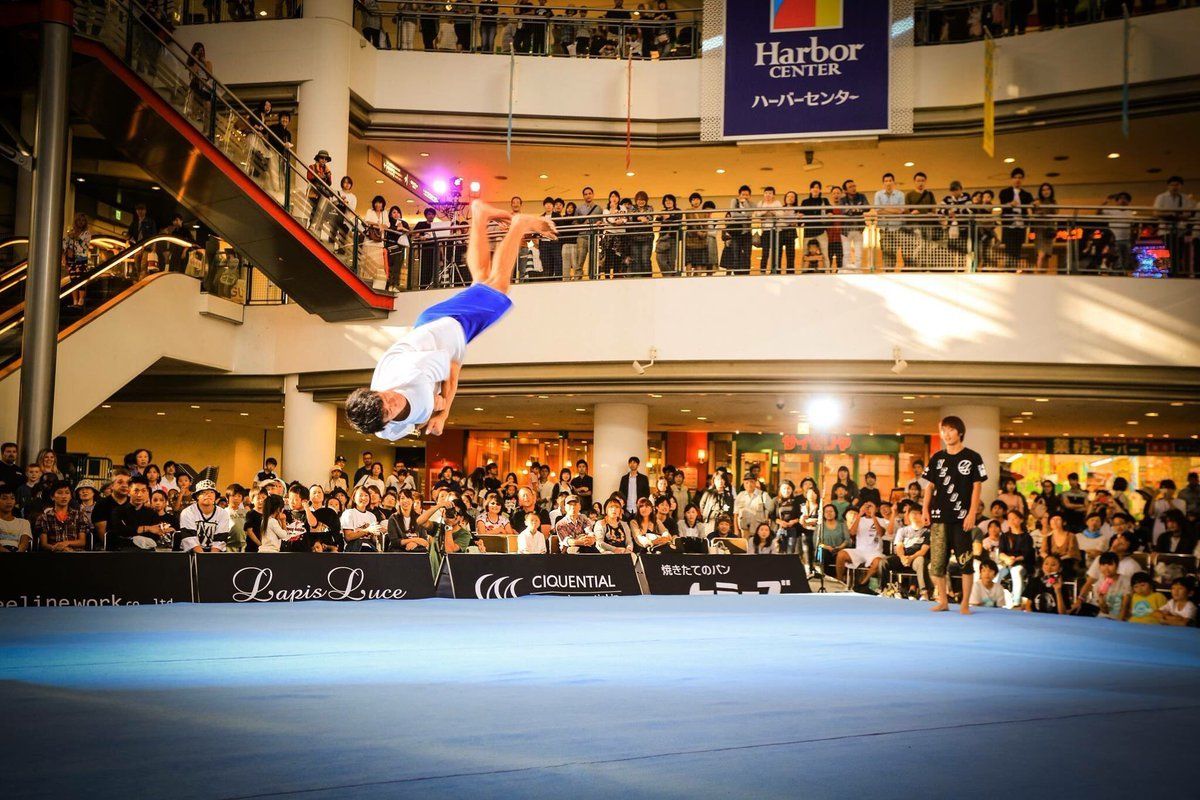 Athlete performing a powerful tricking flip during a live showcase event in front of a large public crowd