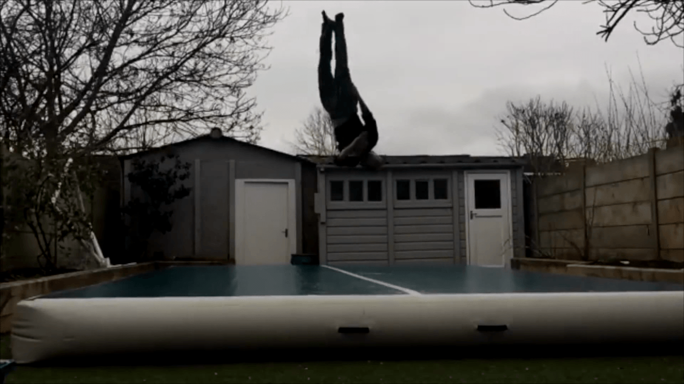 Athlete performing a controlled backflip on an outdoor air track showcasing tricking strength and coordination