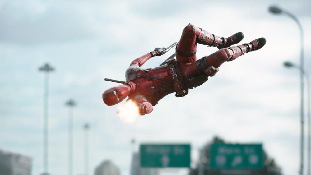 Film stunt performer dressed as Deadpool performing an aerial tricking flip during an action scene