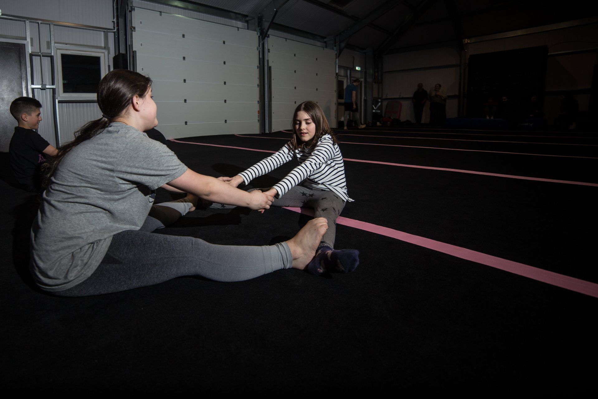 two females practicing their exercises, supporting each other by touching feet and holding hands