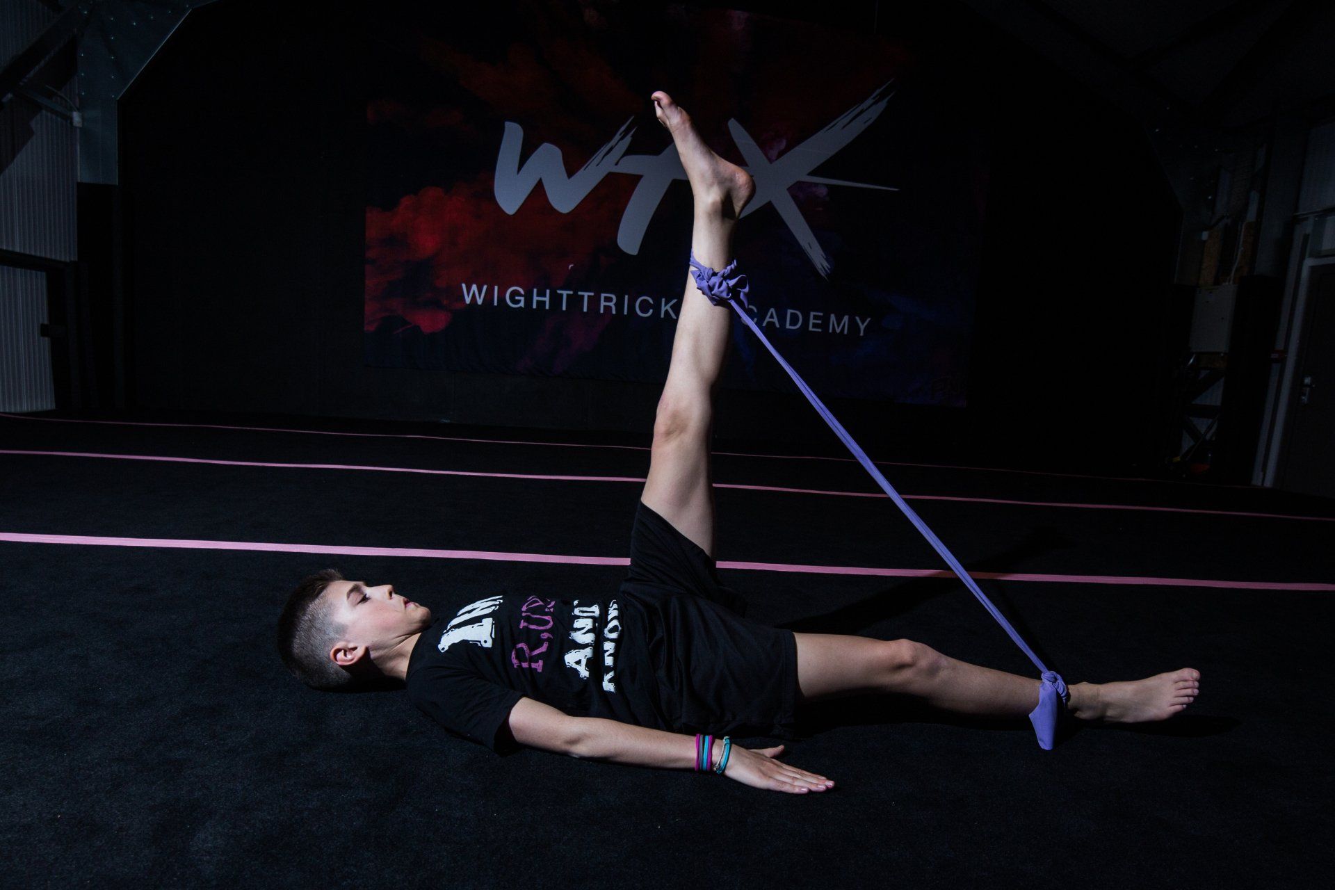 athlete tricker training legs with a bingee style band lying on his back