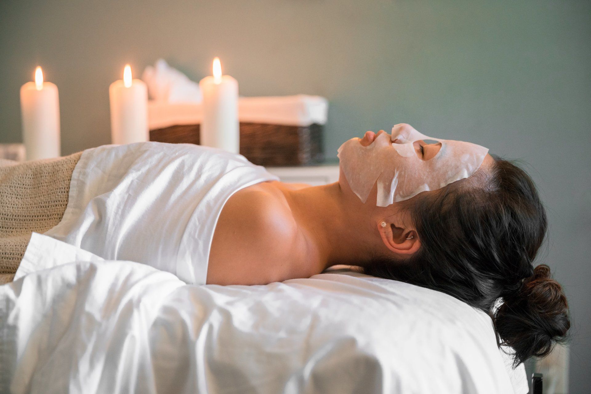 A woman is laying on a massage table with a mask on her face.