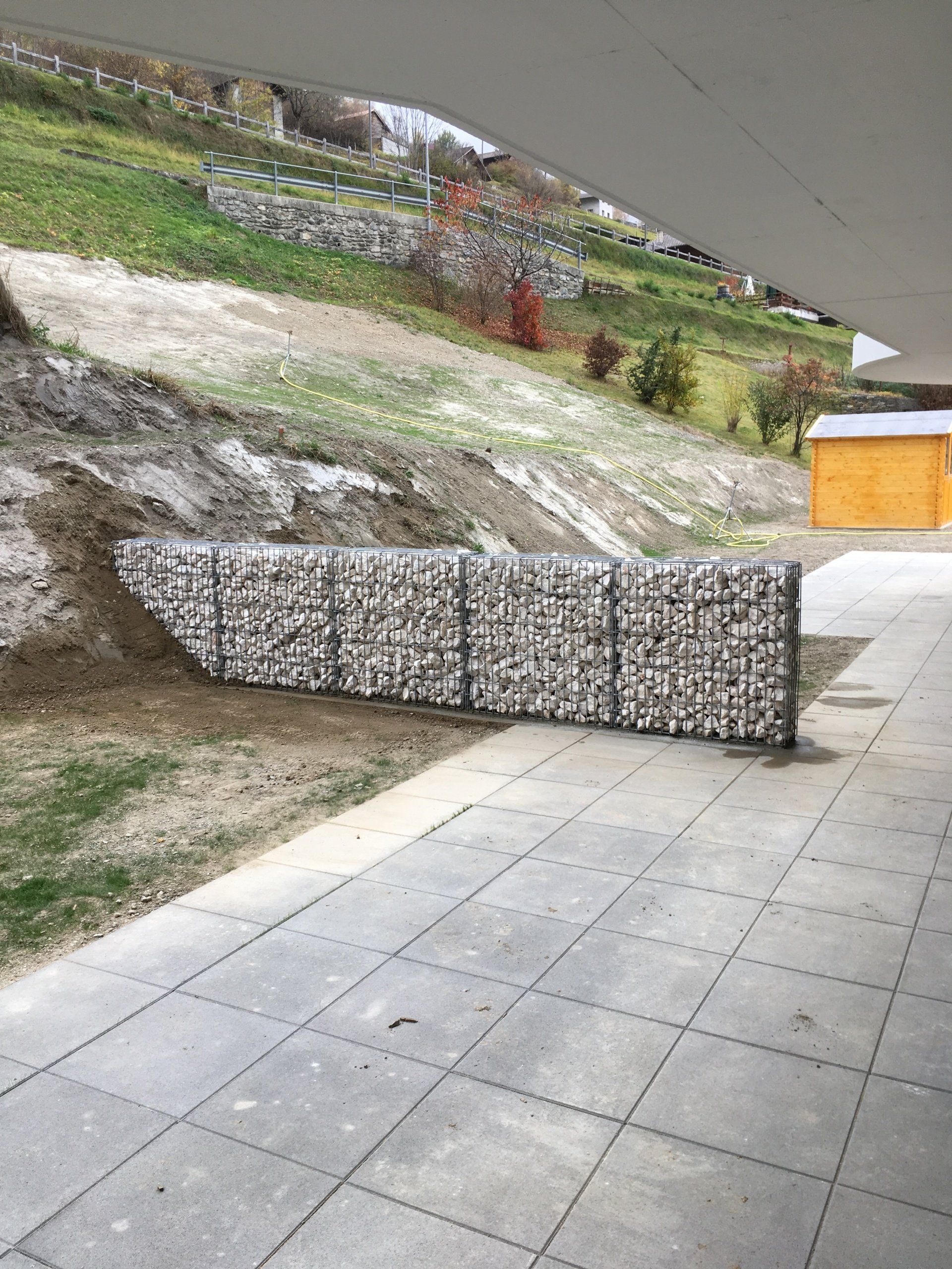 Un mur de pierre est en cours de construction à côté d'une passerelle en béton.