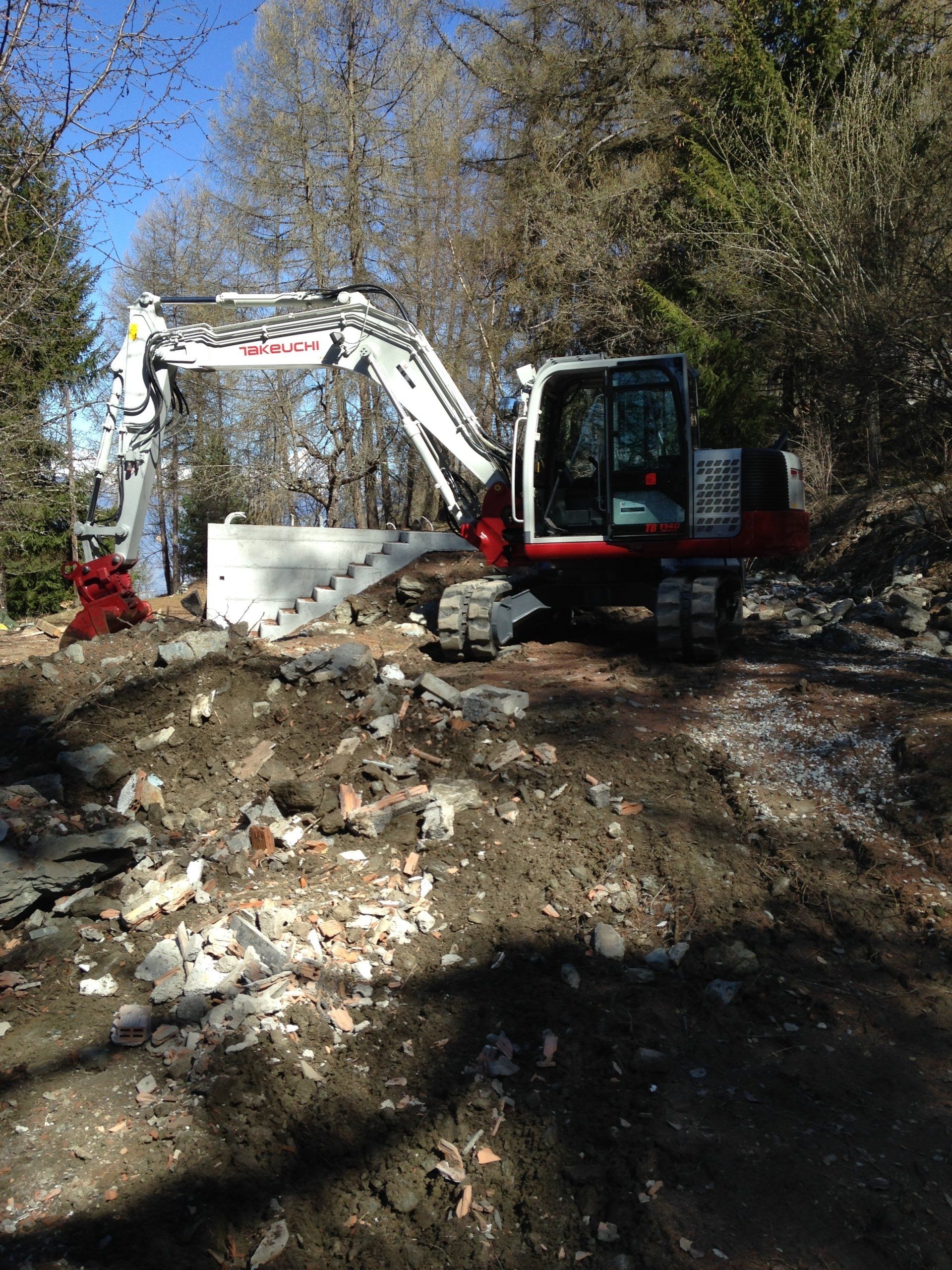 Une excavatrice rouge et blanche est assise sur un chemin de terre.