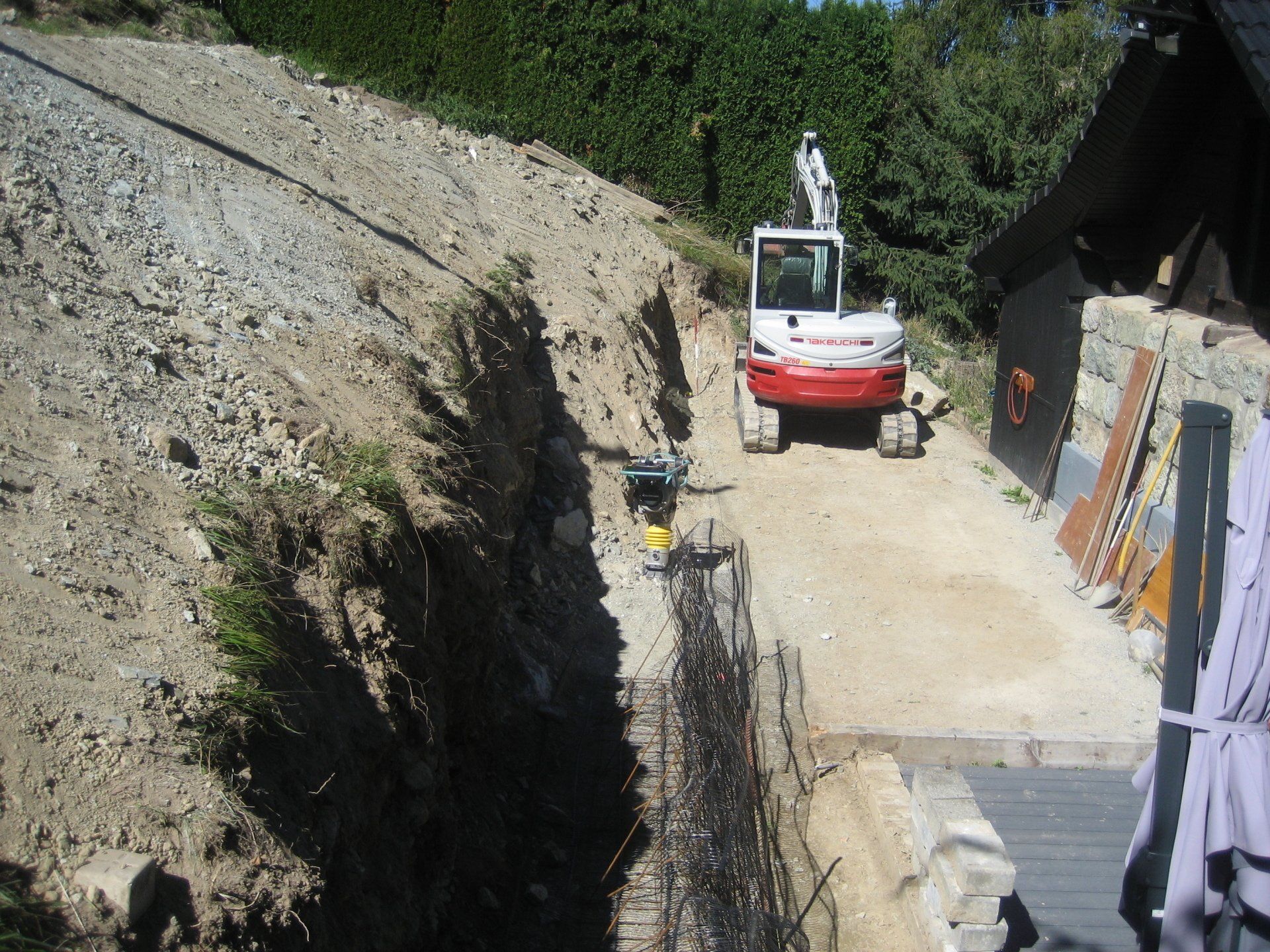 Une excavatrice blanche et rouge roule sur un chemin de terre