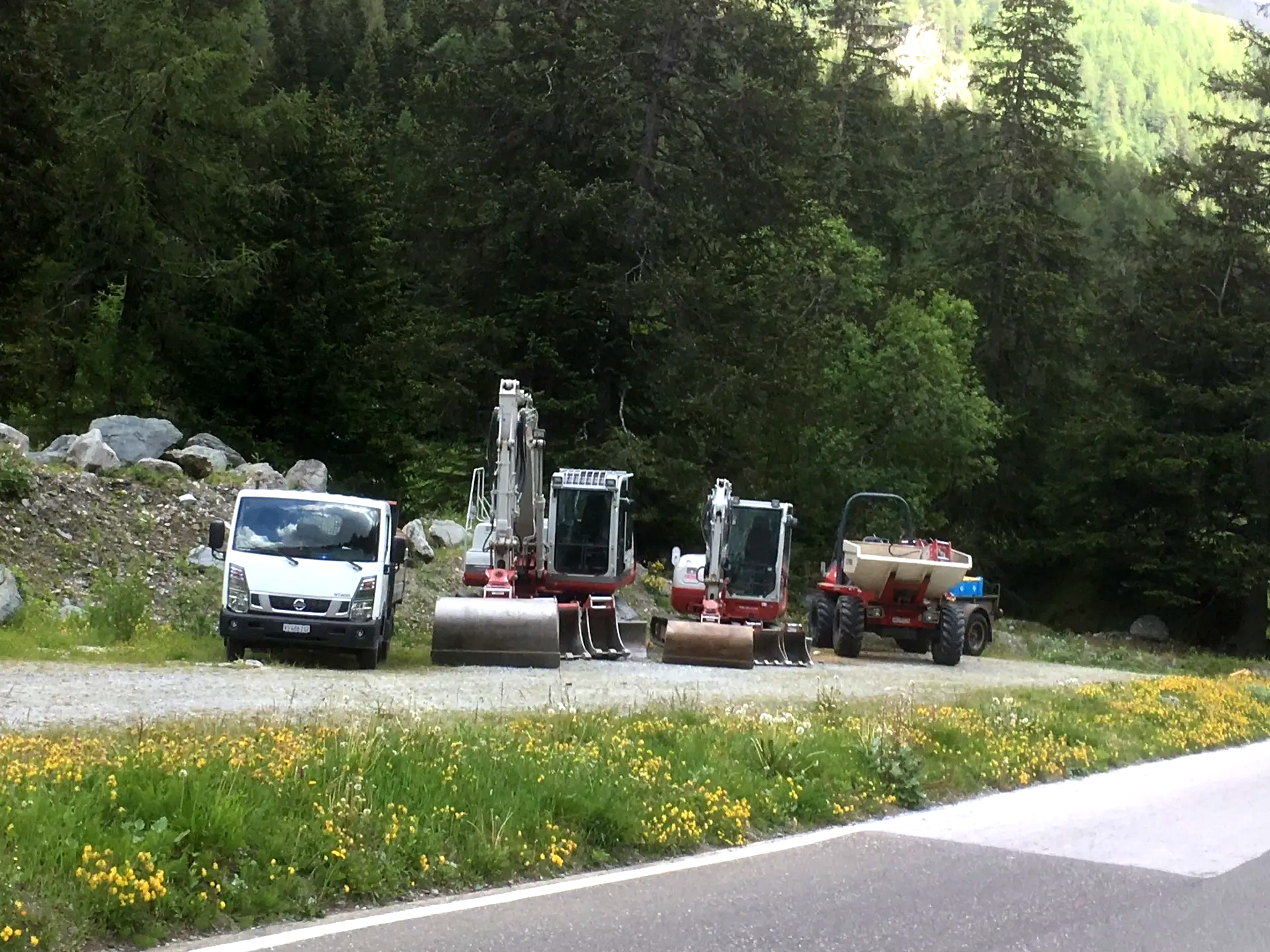 Trois véhicules de construction sont garés sur le bord de la route