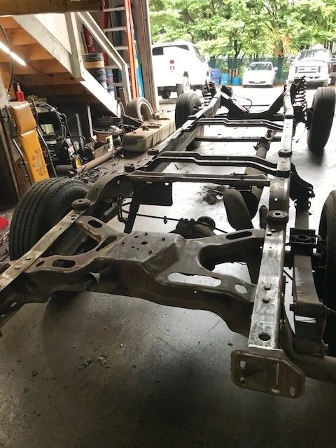 A car chassis is sitting in a garage with a staircase in the background | North County Service Center