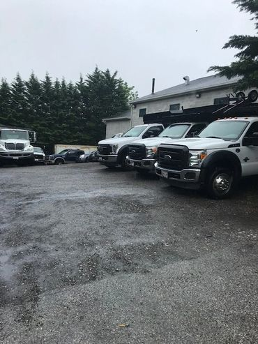 A row of white trucks are parked in a parking lot in front of a building. | North County Service Center