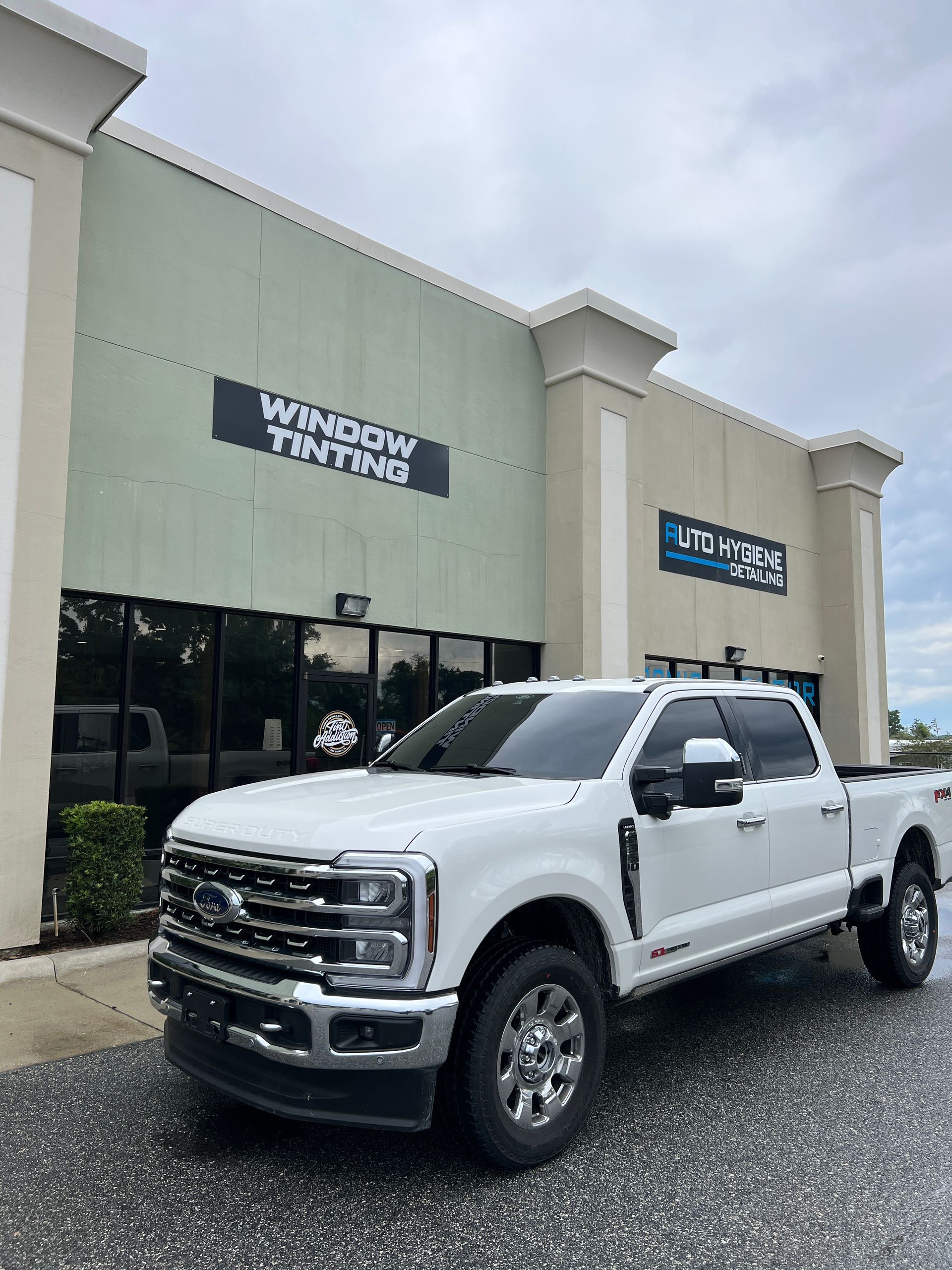 White Ford truck parked in front of a business called 