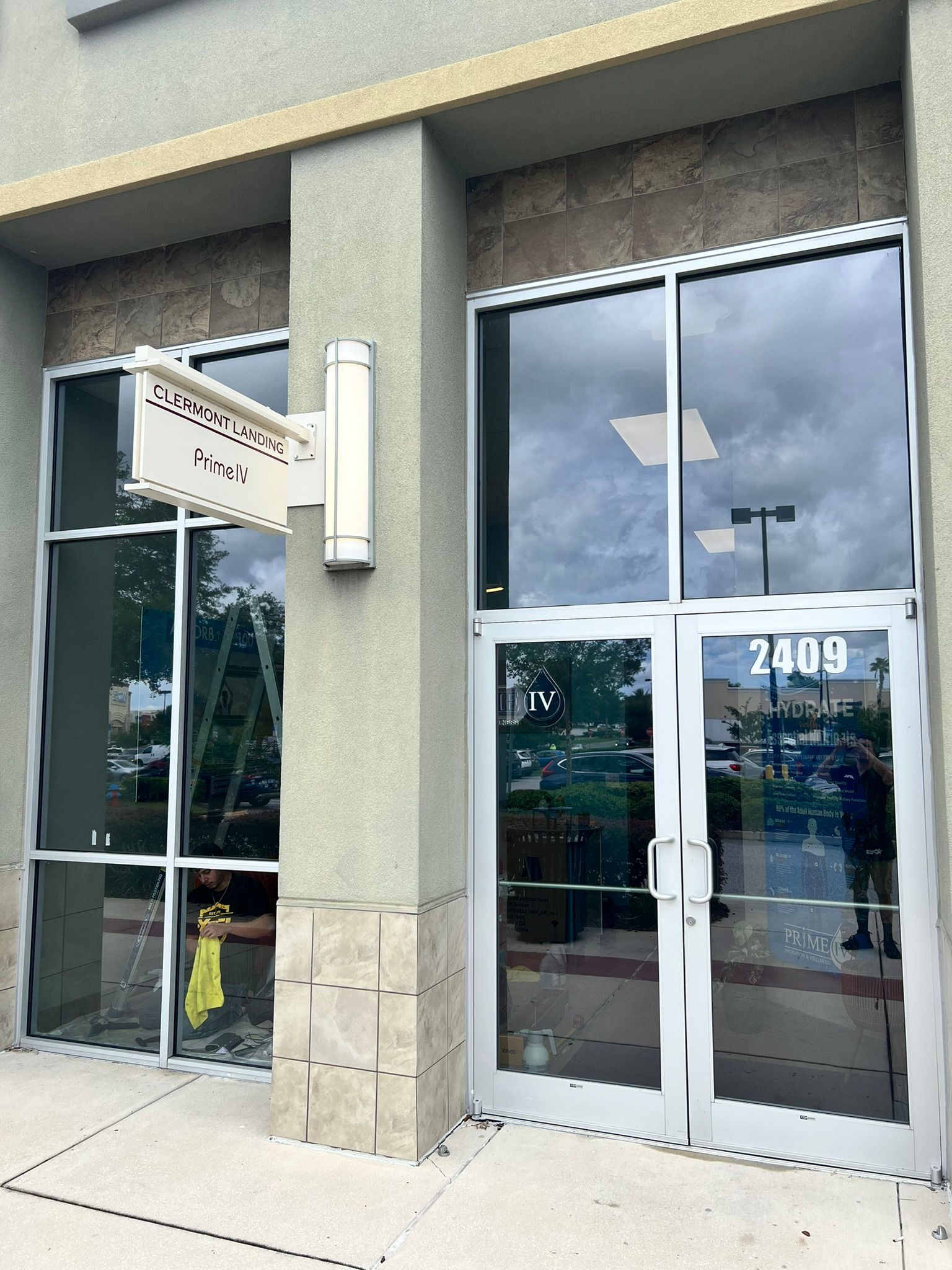 Exterior of a building with glass doors and windows. Sign reads 