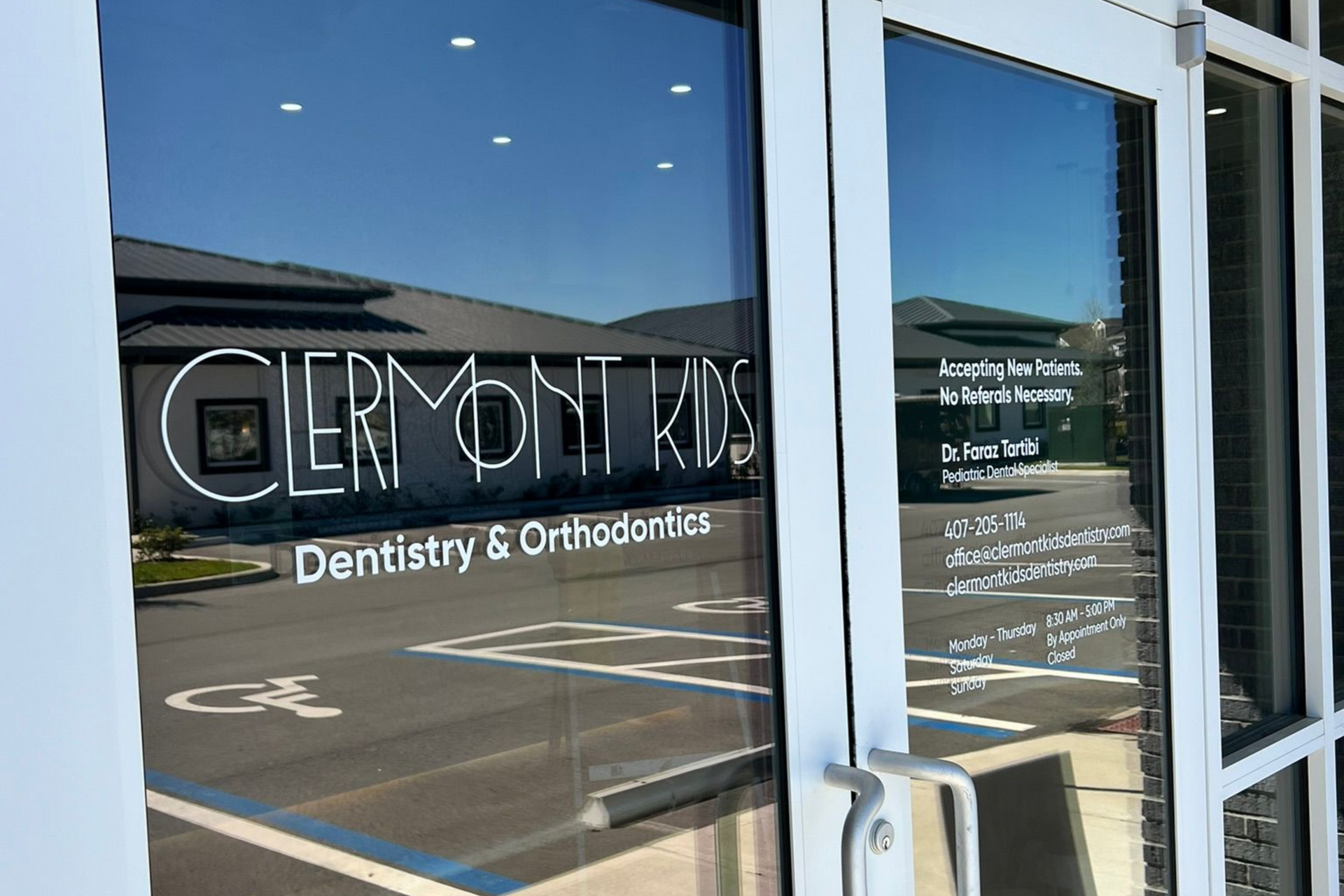 Entrance to Clermont Kids Dentistry & Orthodontics with the name and services visible on the glass door.