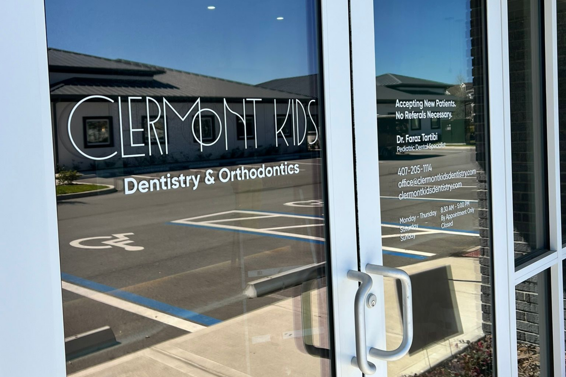 Clermont Kids Dentistry & Orthodontics office entrance; glass door with white lettering, building in background.