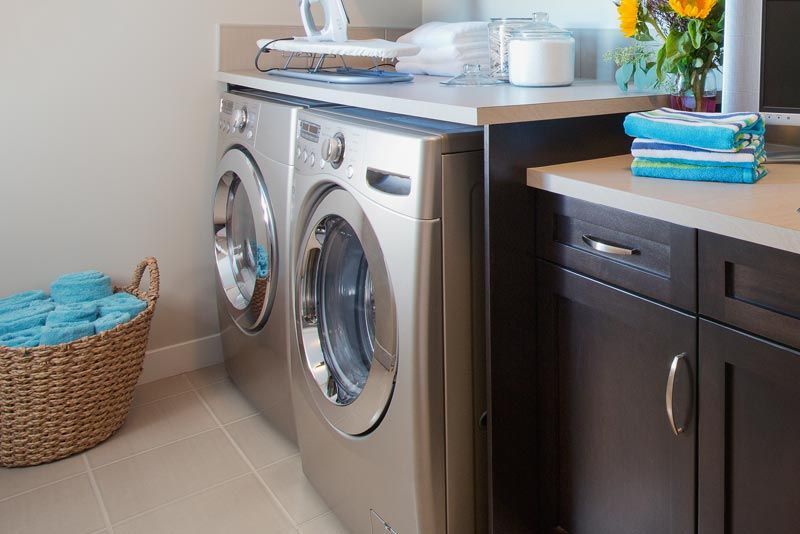 A laundry room with a washer and dryer and a basket of towels.