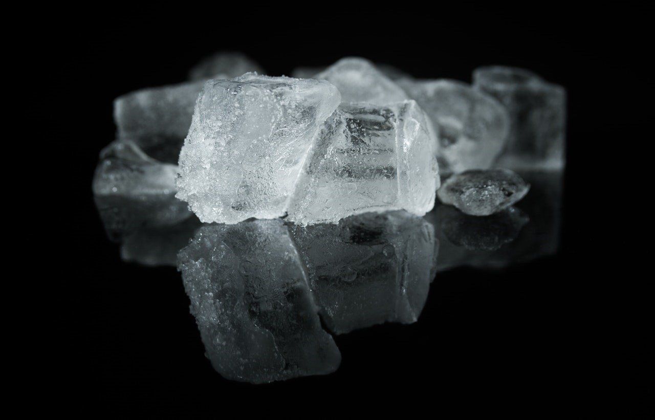 A pile of ice cubes on a black surface.