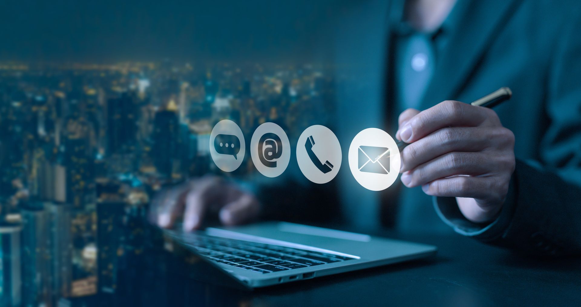 A man is using a laptop computer and holding a pen in his hand.