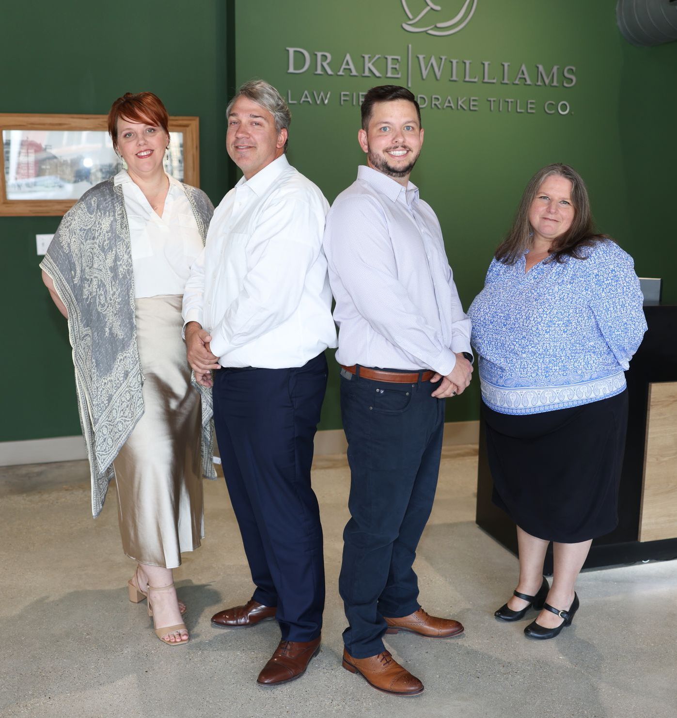 A group of people standing in front of a drake williams sign