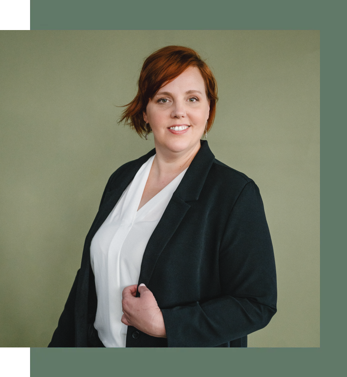 A woman with red hair is wearing a black jacket and a white shirt.