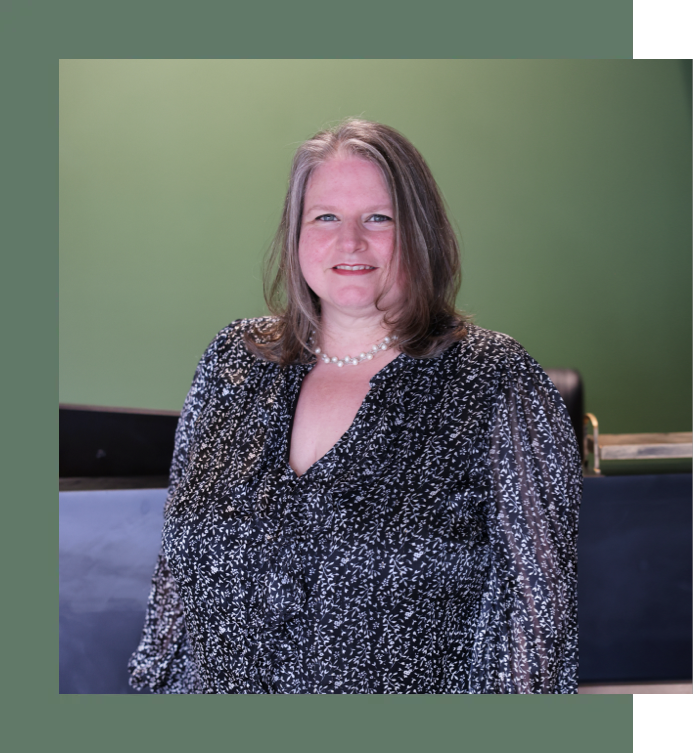 A woman is standing in front of a green wall and smiling