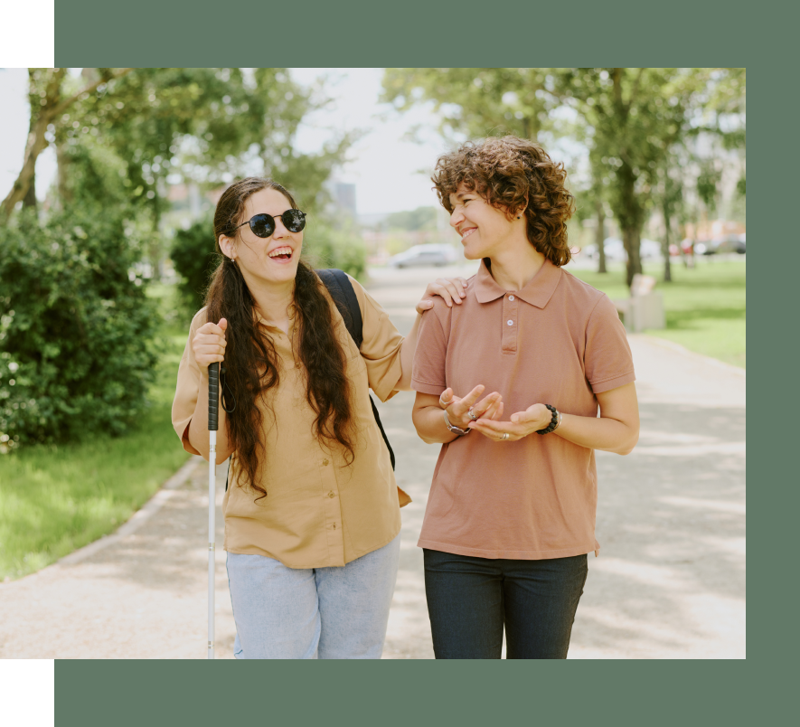 Two women are walking down a sidewalk and talking to each other.