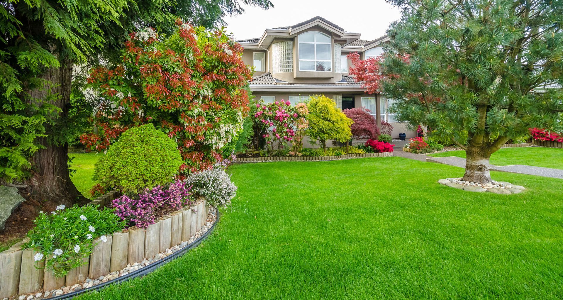 House with lush green lawn and colorful garden.