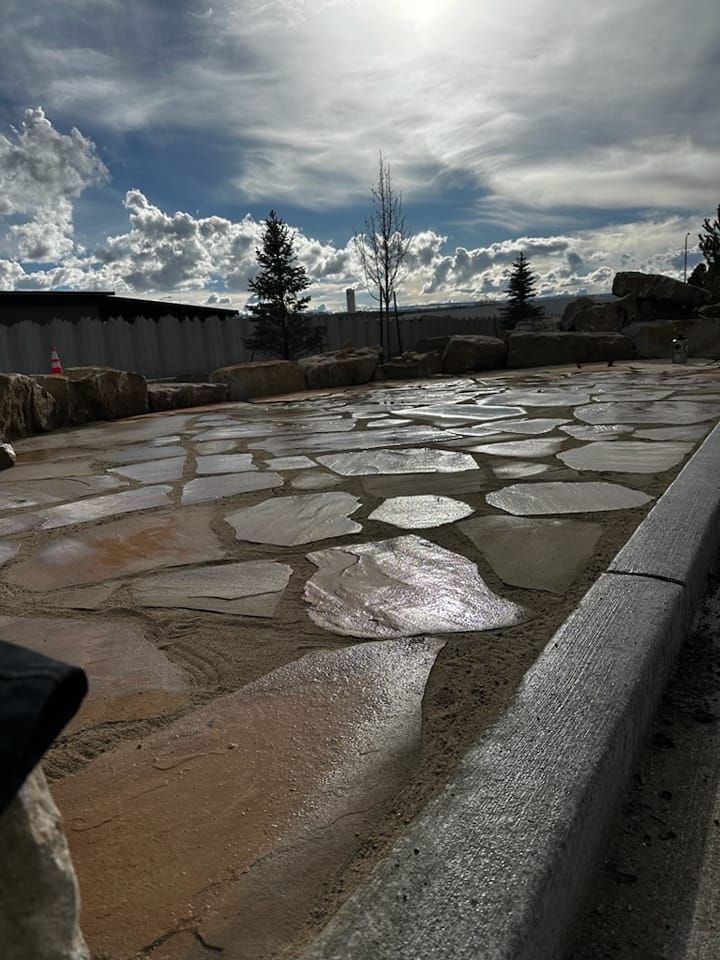 Stone paved walkway, wet from rain, under a cloudy sky.