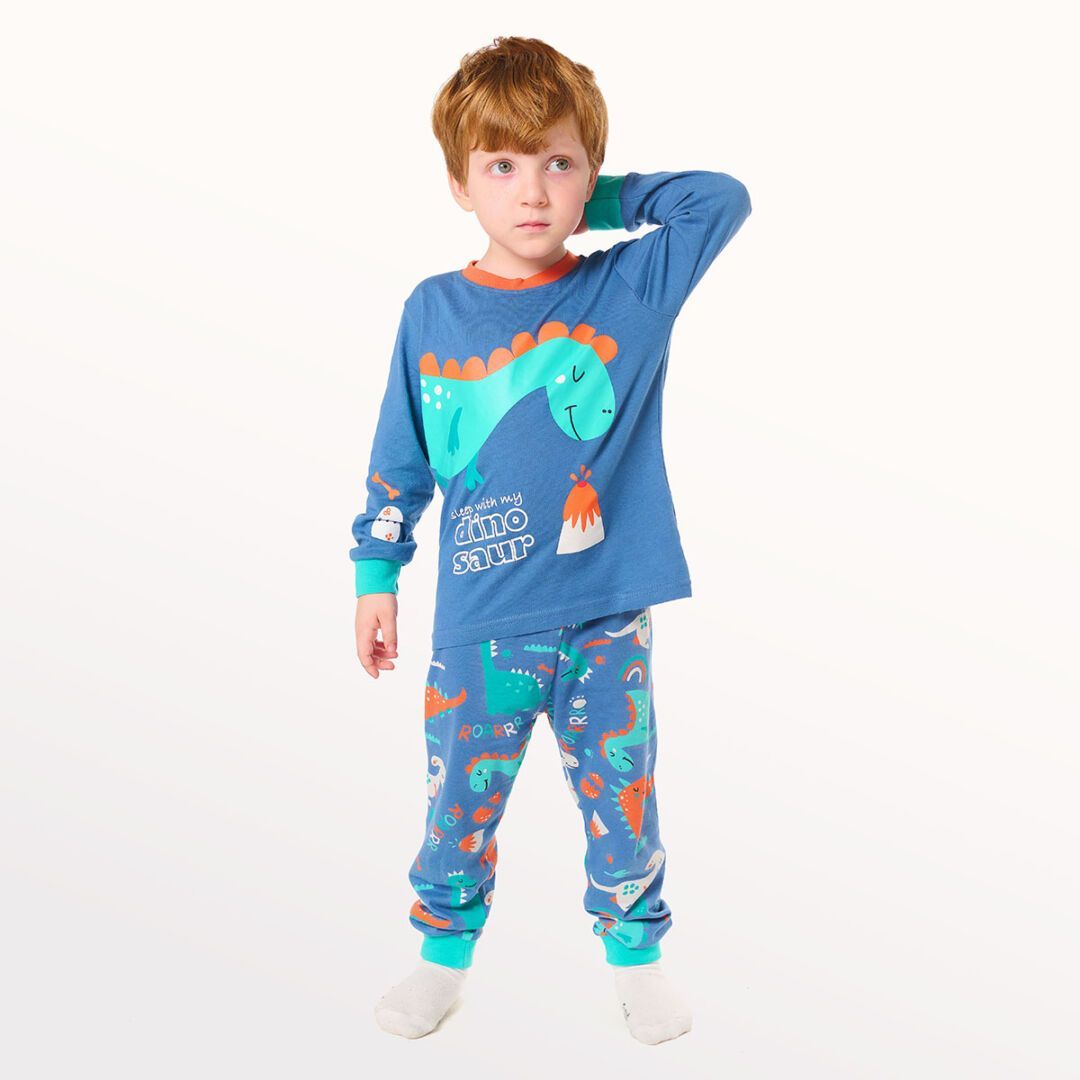 Niña modelando un pijama de dinosaurio azul sobre un fondo blanco.