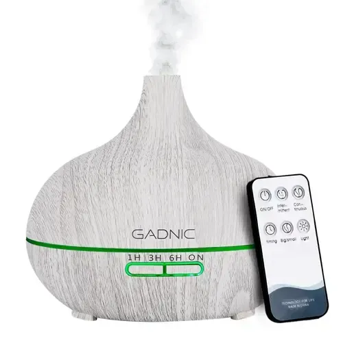 Humidificador GADNIC blanco que libera niebla junto a un pequeño mando a distancia.