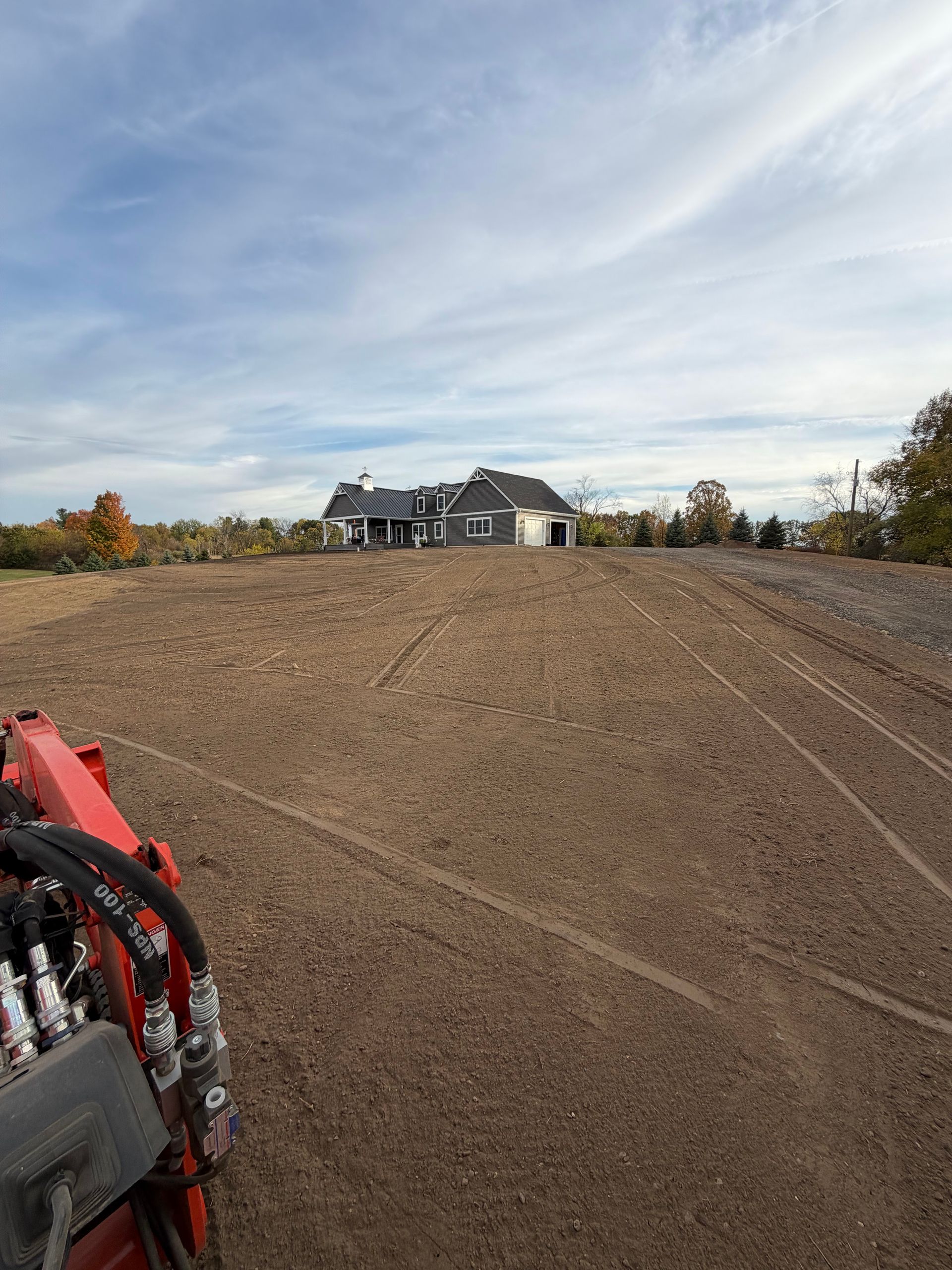 A large empty lot with a new house under construction in the distance.