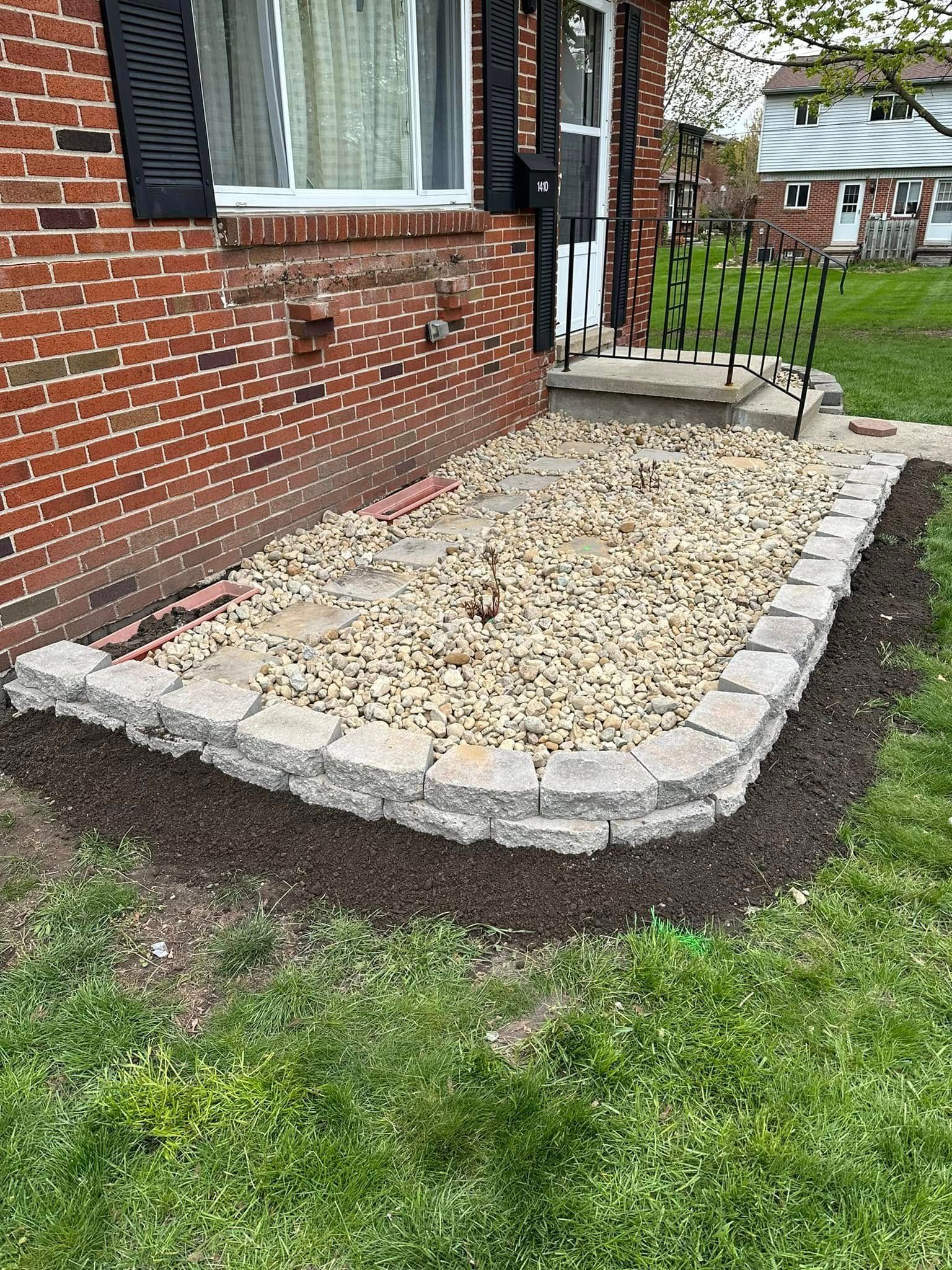 Brick house with a rock garden bed outlined by gray stones, filled with tan pebbles.